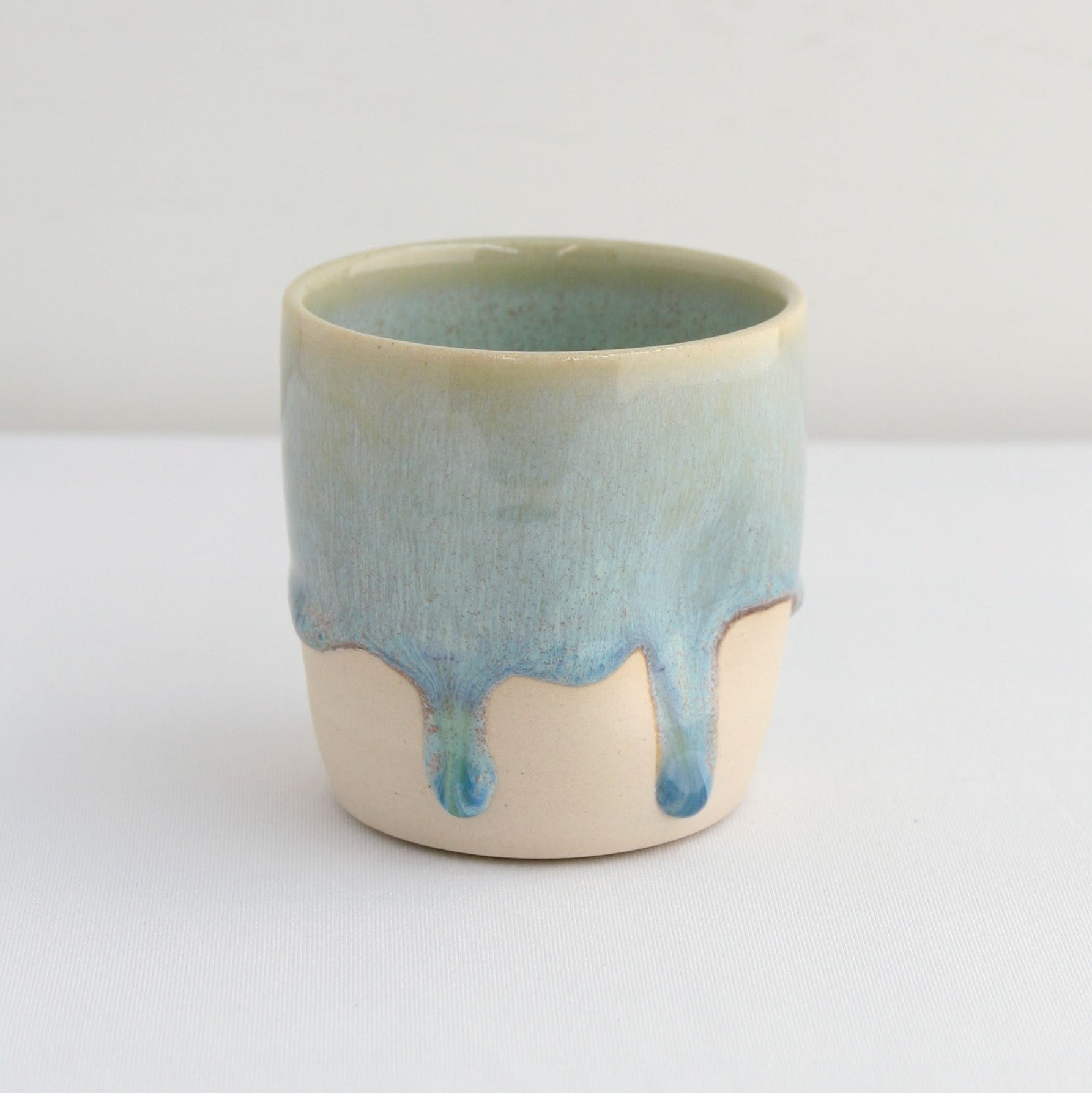 Ceramic cup with green glaze on a white background