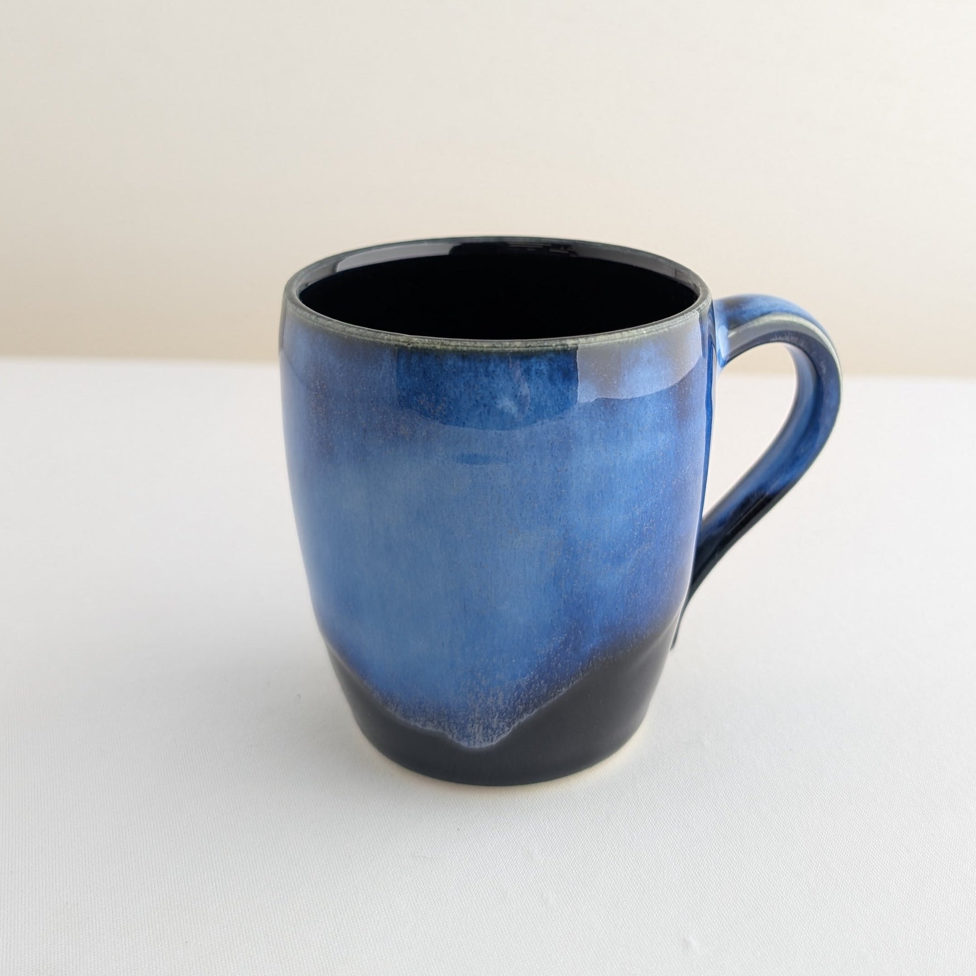 Blue ceramic mug with black interior on a white surface