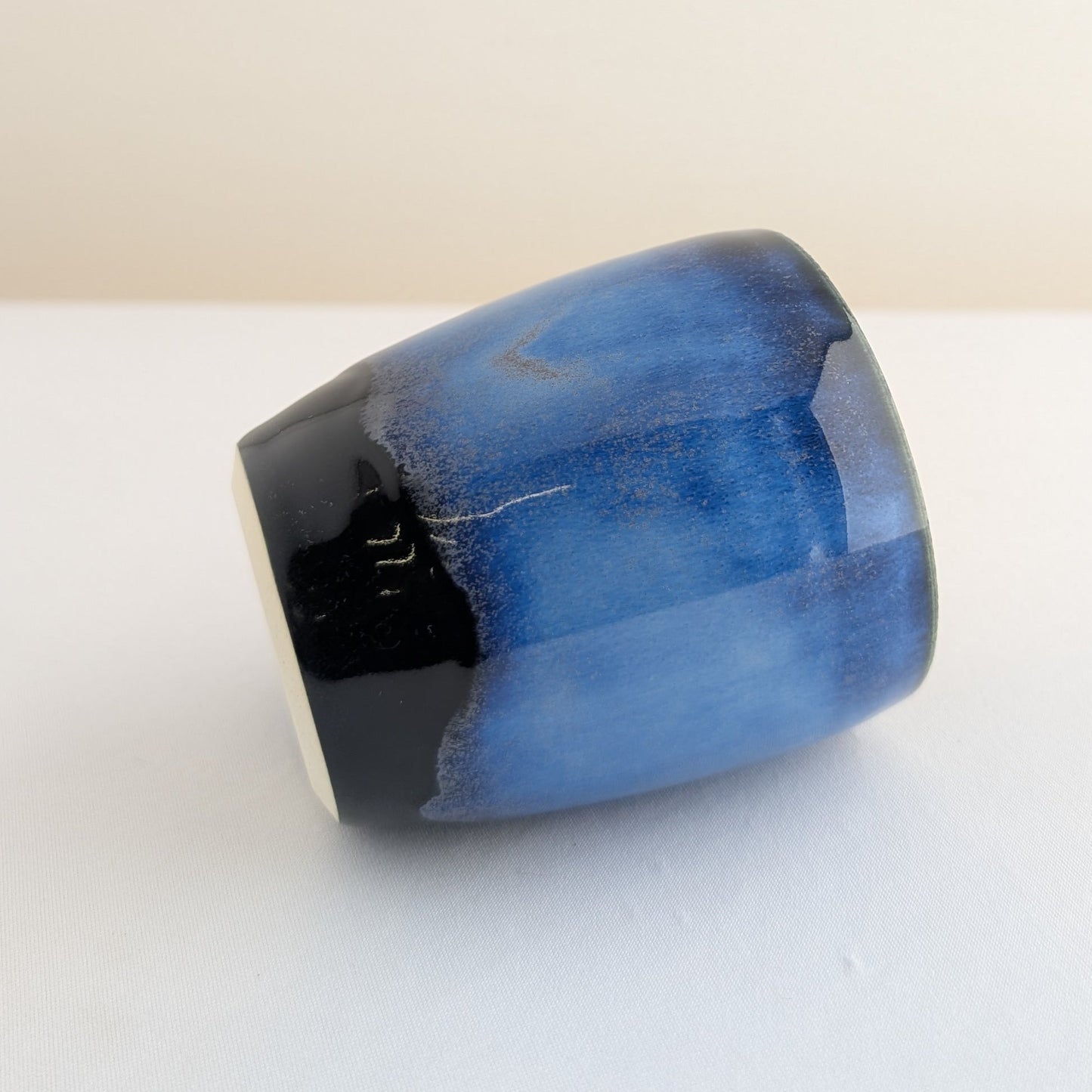 Blue ceramic cup on a white surface with a beige background