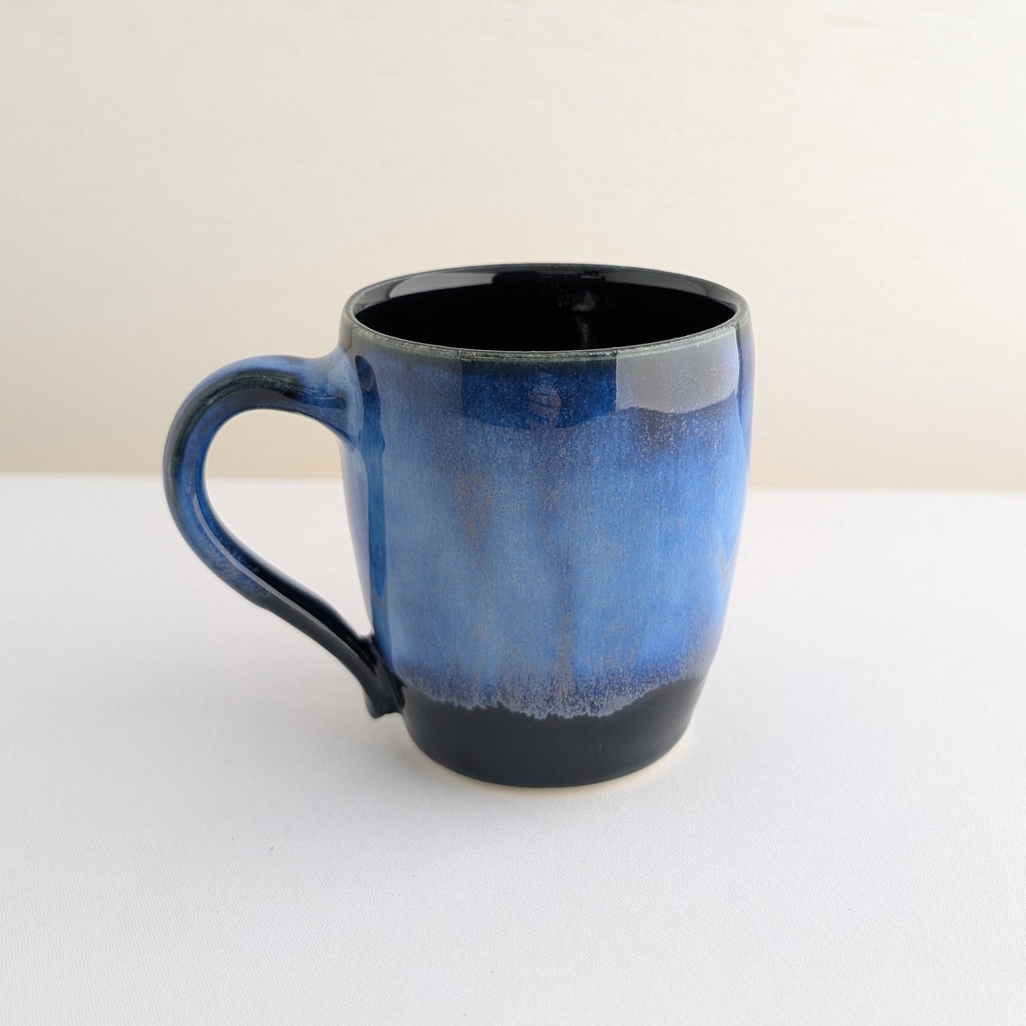 Blue ceramic mug with black interior on a white background