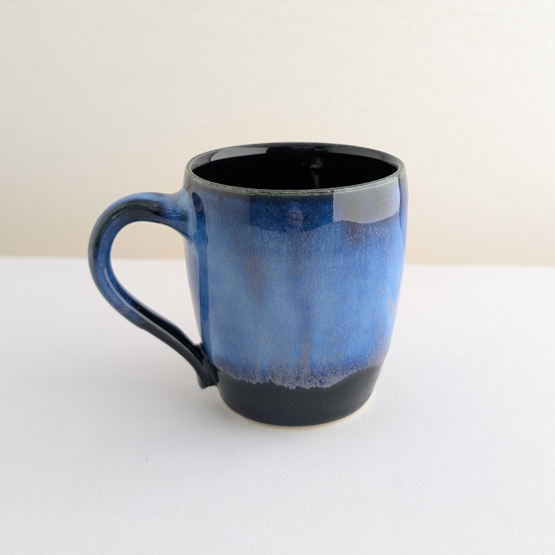 Blue ceramic mug with black interior on a white background